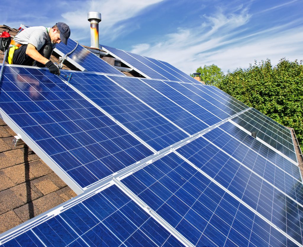 Man installing alternative energy photovoltaic solar panels on roof